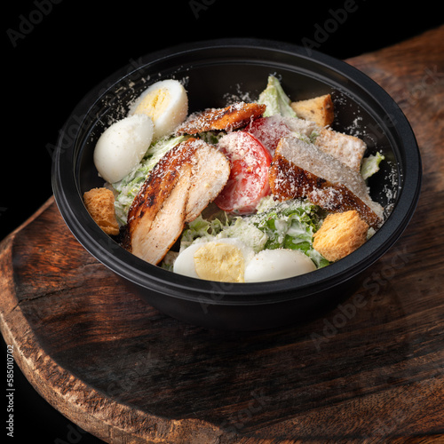 Caesar salad in round black lunchbox