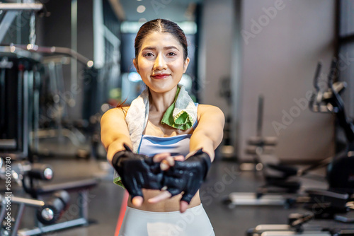 Active young Asian woman stretching her body warm up before intensive workout at gym, basic gym exercises performed by the young female