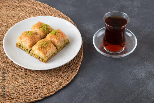 Pistachio baklava on a white plate with Turkish tea.A plate of traditional baklava on black background
