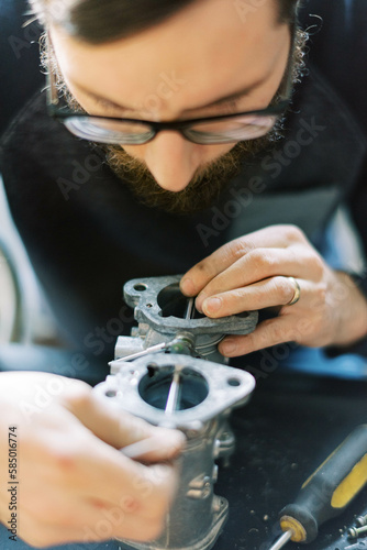Millennial Man assembling carburetor on kitchen table in his home  photo
