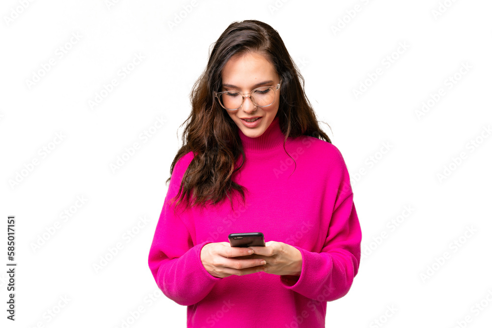 Young caucasian woman isolated over isolated background sending a message with the mobile Young caucasian woman isolated over isolated background sending a message with the mobile