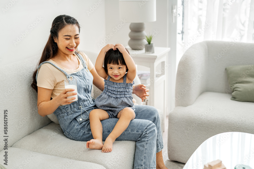 Asian mother gives a glass of milk to her daughter for breakfast Asian mother gives a glass of milk to her daughter for breakfast