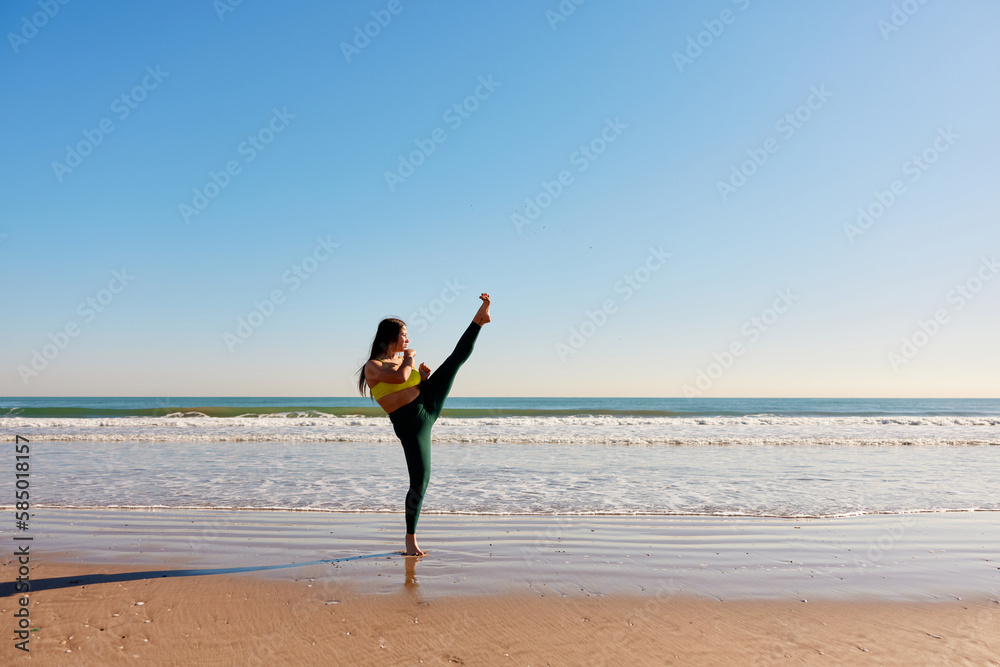 Sportswoman performing karate kick on beach Sportswoman performing karate kick on beach