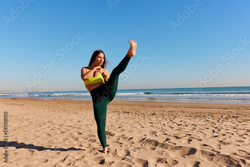 Sportswoman performing karate kick on beach photo
