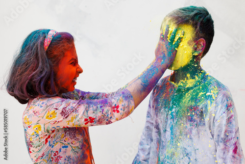 Brother and sister playing holi together with color powder photo