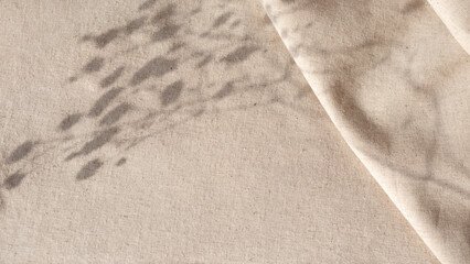 Aesthetic natural minimalistic background, elegant sunlight floral shadows on neutral beige linen texture pleated tablecloth, background with copy space