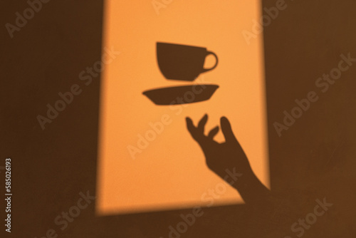 Shadow of a hand throwing a cup of coffee into the air