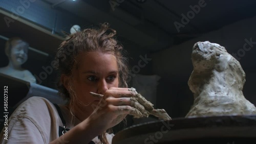 European blonde girl sculptor creates sculpture, statue for interior, bozzetto. The woman has her own local business, a freelancer. The female uses the tools of a sculptor, stecca for clay. photo