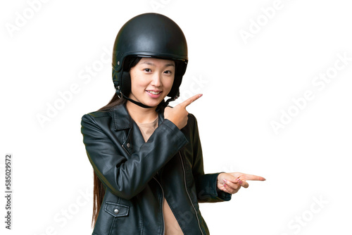 Young Asian woman with a motorcycle helmet over isolated chroma key background surprised and pointing side © luismolinero
