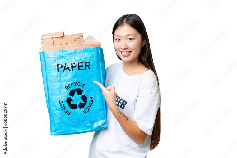 Young Asian woman holding a recycling bag full of paper to recycle over isolated chroma key background and pointing it Young Asian woman holding a recycling bag full of paper to recycle over isolated chroma key background and pointing it