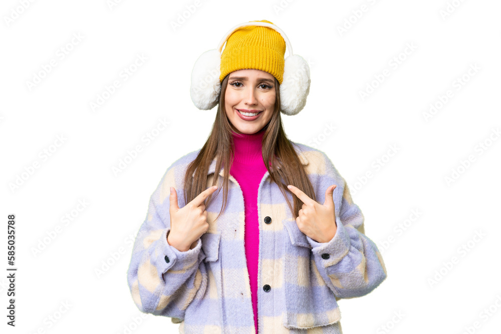 Young woman wearing winter muffs over isolated chroma key background with surprise facial expression Young woman wearing winter muffs over isolated chroma key background with surprise facial expression