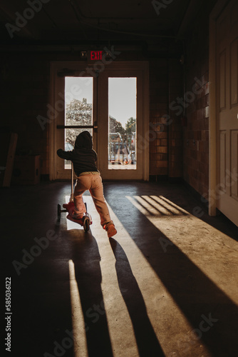 Girl on scooter in dramatic shadow light in front of glass door photo