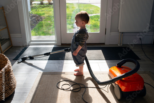Helpful Toddler Standing in Entryway Vacuuming Rug