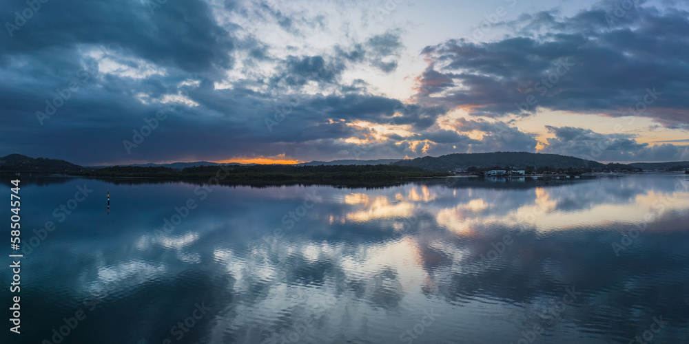 Obraz premium Sunrise waterscape panorama with rain clouds and reflections
