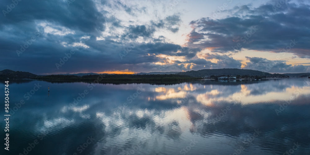 Sunrise waterscape panorama with rain clouds and reflections