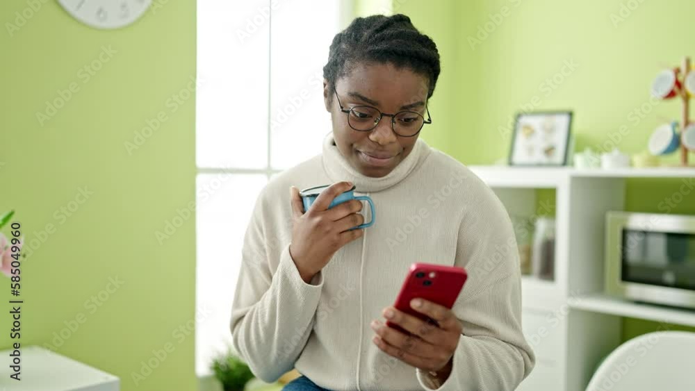 African american woman using smartphone drinking coffee at dinning room