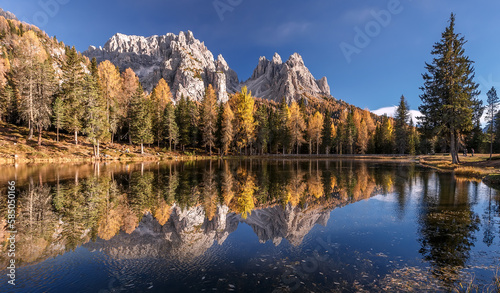 Fototapeta Naklejka Na Ścianę i Meble -   Inckedible autumn scenery with reflections. Amazing autumn landscape in the mountains with yellow larches and lake glowing by sun and high mountain peaks behind. Antorno lake. Picture of Wild area.