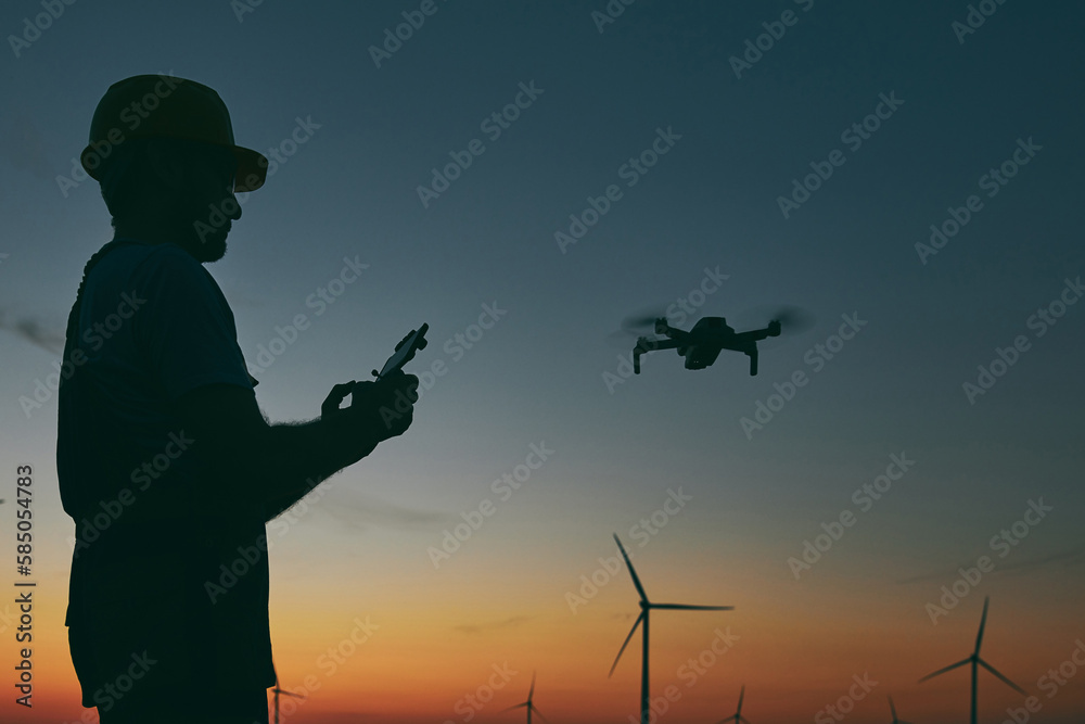 Engineer mechanic using drone for inspection in a windmill farm park.