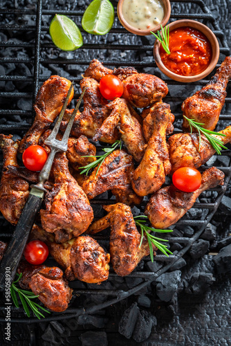 Tasty roasted chicken leg on black metal grill plate.