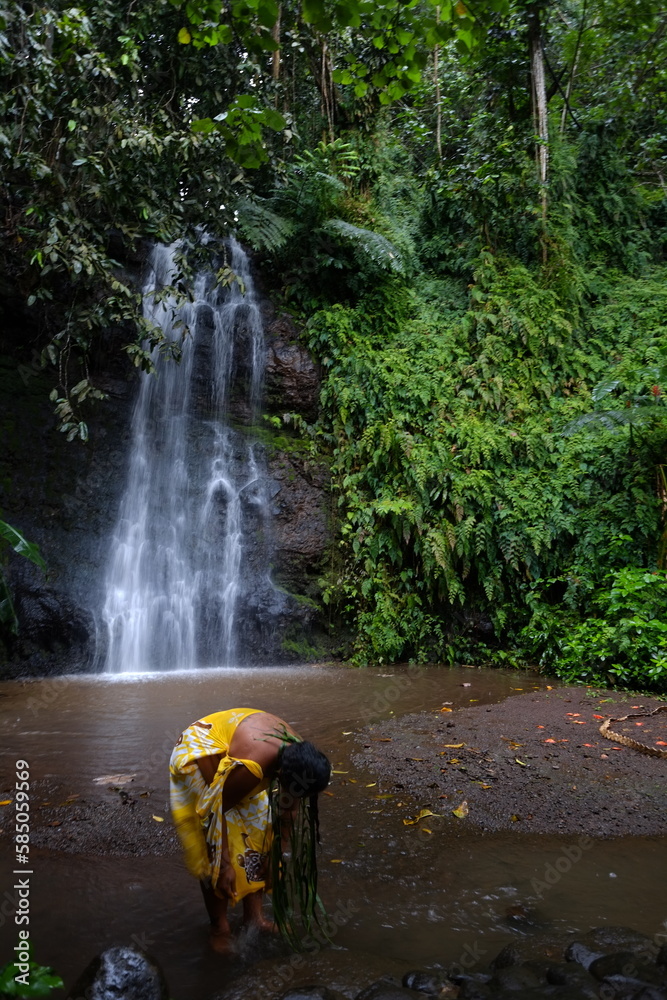 Φωτογραφία A tahitian woman doing a purification act in the water in a small pond of a scenic waterfall
