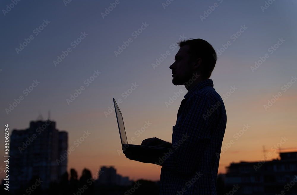 custom made wallpaper toronto digitalHardly working evening. Freelance male developer or it engineer working outdoor using laptop in silhouette at sunset with urban background. Adorable dusk at background. High quality image