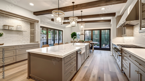 Traditional kitchen in beautiful new luxury home with hardwood floors, wood beams, and large island quartz counters. Includes farmhouse sink, elegant pendant lights, and large windows.