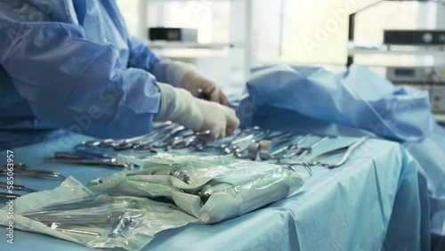 Preparation for the surgery. Surgery tools. Multiple surgery tools on the table in operating room. Scrub nurse hands in rubber gloves. Modern medical concept.