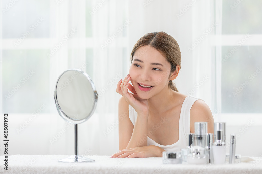Happy Asian young woman smile and looking in mirror doing skin care touch cheek and beauty treatment at home,Wellness woman self care with beauty product at home Happy Asian young woman smile and looking in mirror doing skin care touch cheek and beauty treatment at home,Wellness woman self care with beauty product at home