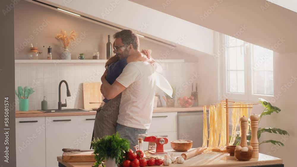 Loving couple standing hugging in the kitchen, covered with flour. A man takes a handful of flour and sprinkles it on the woman. Flour battle Loving couple standing hugging in the kitchen, covered with flour. A man takes a handful of flour and sprinkles it on the woman. Flour battle