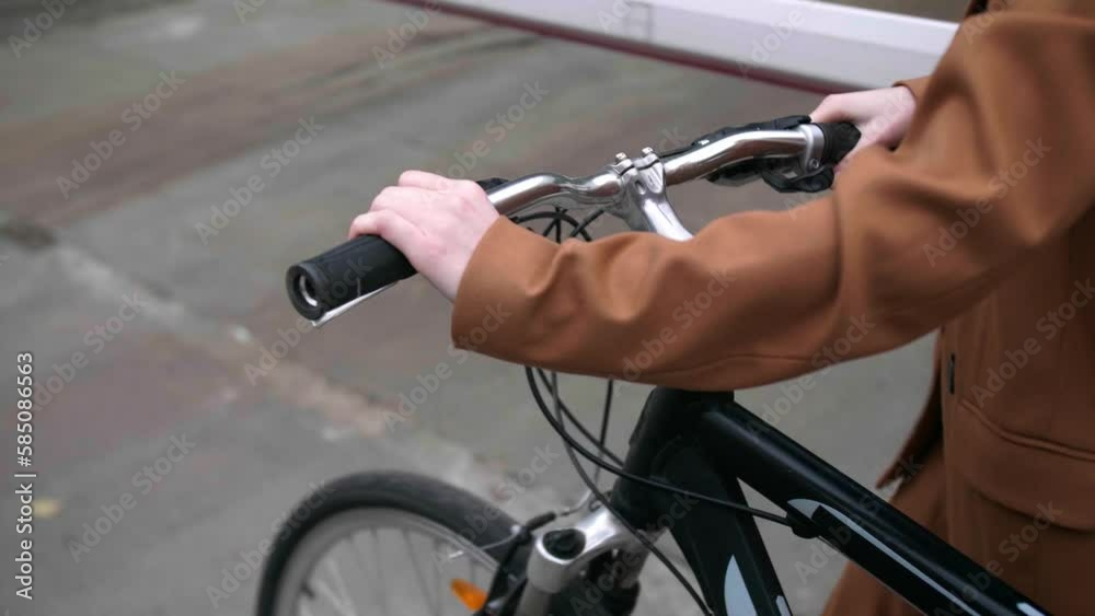 Young woman with bicycle walking on street, closeup view. Camera moving forward, slow motion effect