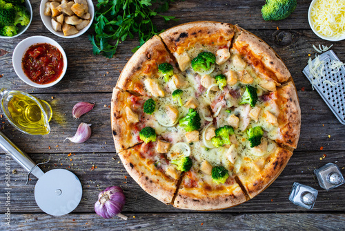 Circle pizza broccoli with chicken nuggets and mozzarella cheese on wooden table
