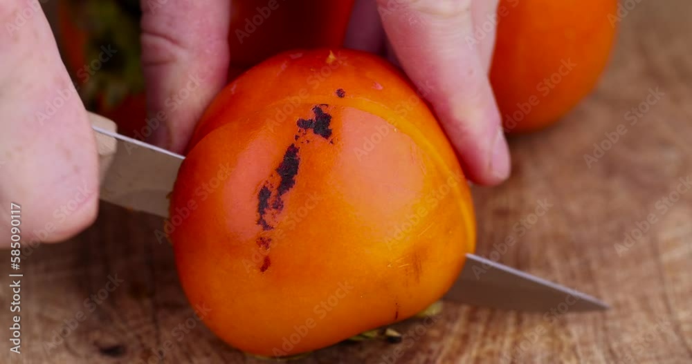 Half-ripe orange persimmon, fresh ripe persimmon cut into pieces on a cutting board with a sharp knife