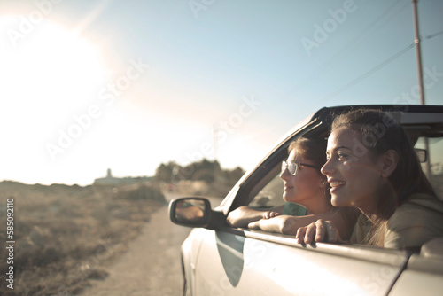 portrait of two smiling young women in a convertible car