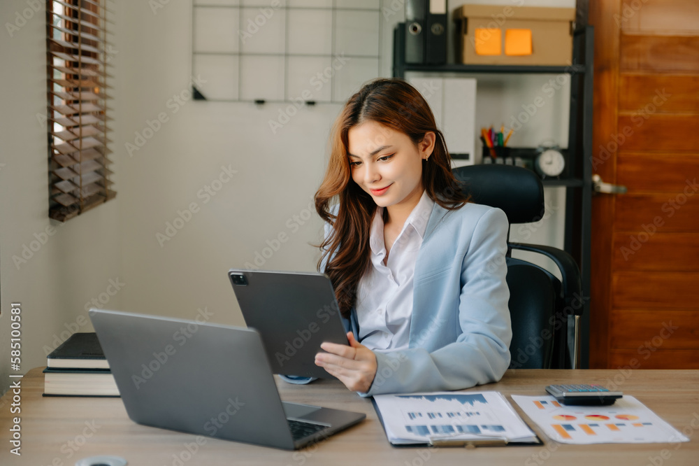 Business woman using tablet and laptop for doing math finance on an office desk, tax, report, accounting, statistics, and analytical research concept in office Business woman using tablet and laptop for doing math finance on an office desk, tax, report, accounting, statistics, and analytical research concept in office