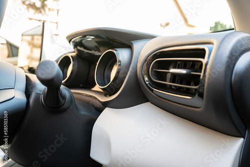 Cockpit view of a new, Japanese hybrid hatchback car. Showing the dual LCD dashboard and air con vent. The car is located at a car dealership. © Nick Beer