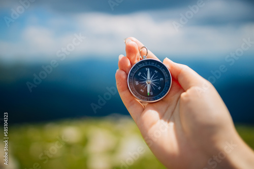 Traveler with compass seeking a right way in the mountains during hike. Navigation concept in explore travel.