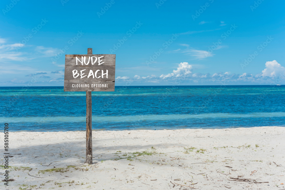 A nude beach sign posted at the beachfront. A nudist beach or naturist resort.