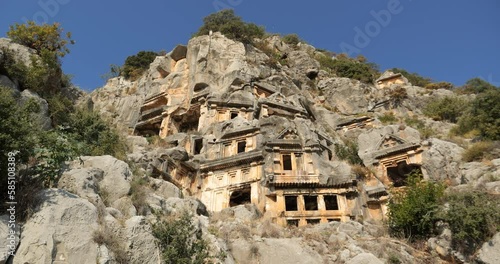 Ruins of ancient Lycian tombs carved into the rock on territory of the city of Demre Mira Limira in the Turkish province of Antalya. Concept of tourists visiting ancient cultural monuments photo