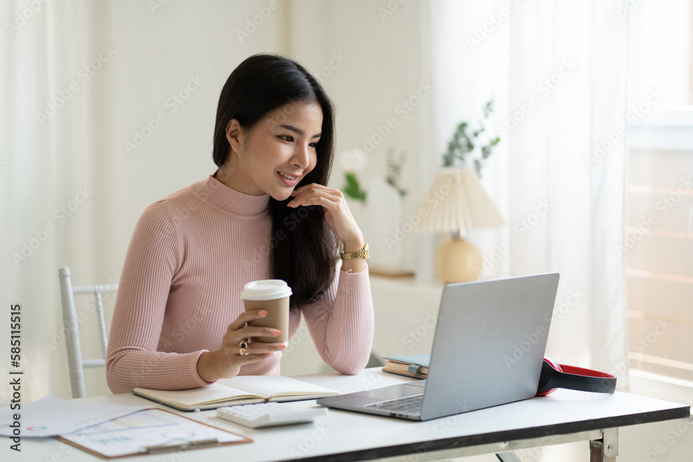 Young gorgeous business woman working and holding a cup of coffee in her hand while working.. Young gorgeous business woman working and holding a cup of coffee in her hand while working..