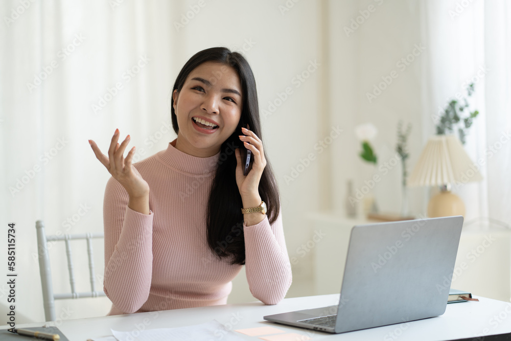 Adorable young Asian woman having a phone call while sitting in a comfortable room. Adorable young Asian woman having a phone call while sitting in a comfortable room.