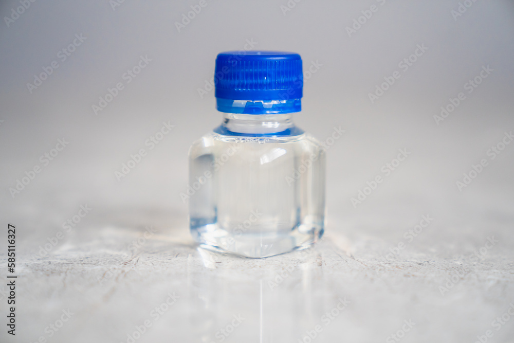 Smallest plastic bottle with a blue cap with transparent chemical liquid inside Smallest plastic bottle with a blue cap with transparent chemical liquid inside