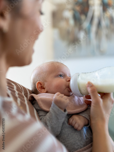 Foto Mother feeding baby with milk from bottle