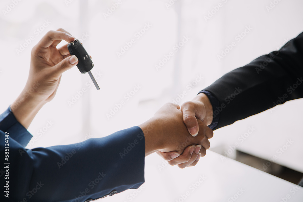 A car rental company employee is handing out the car keys to the renter ...