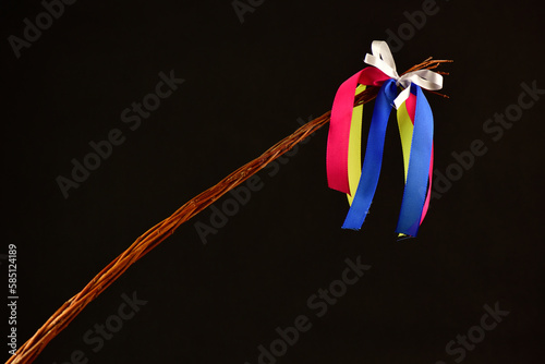 Traditional Czech Easter whip with colored ribbons 
from willow branches on the black background 