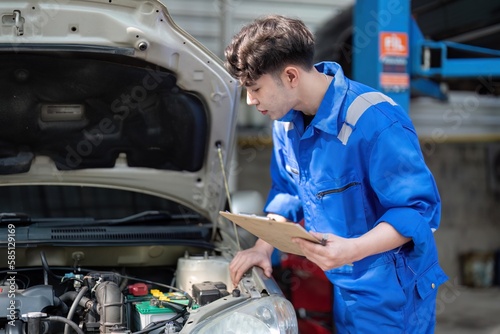 Vehicle service maintenance asian man checking under car condition in garage. Automotive mechanic maintenance checklist document. Car repair service concept