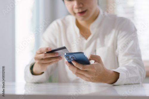 Cropped shot of millennial man is paying with a credit card online while placing orders via mobile internet and making transactions using a mobile banking application.