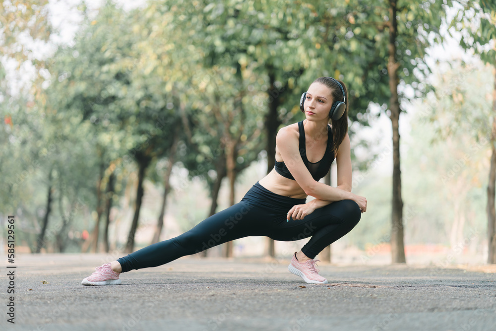 A young female athlete, dressed for running, is shown stretching her legs in preparation for a jog through the park. A young female athlete, dressed for running, is shown stretching her legs in preparation for a jog through the park.
