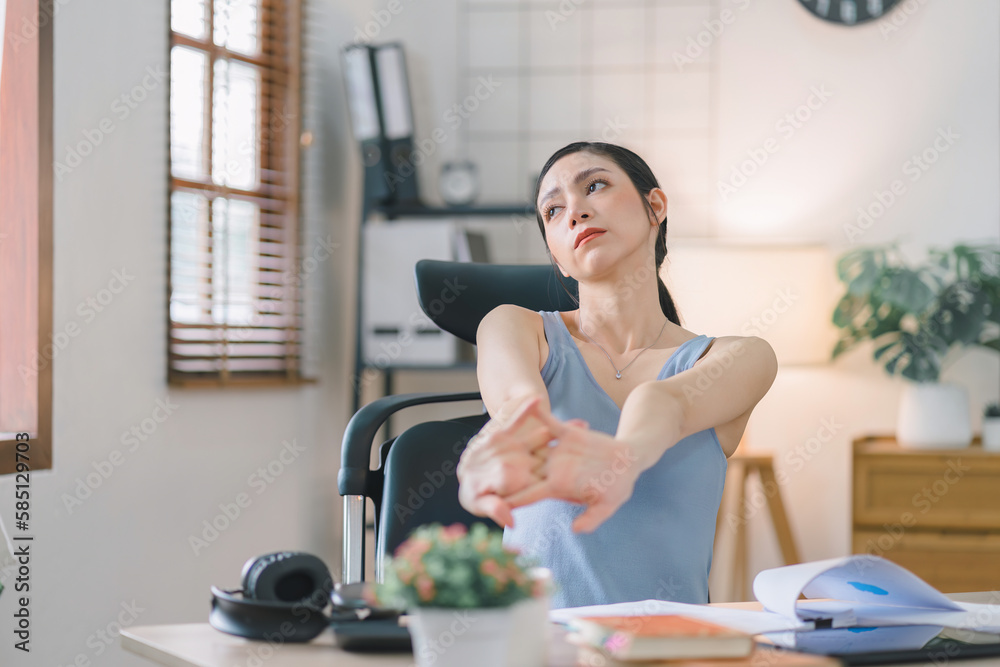 An attractive millennial businesswoman is stretching her arms during a break at her home office. An attractive millennial businesswoman is stretching her arms during a break at her home office.