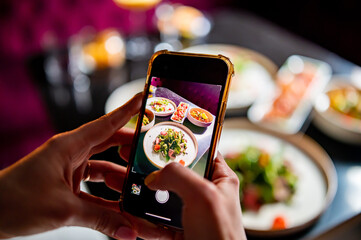 hand with smartphone photographing food at restaurant or cafe