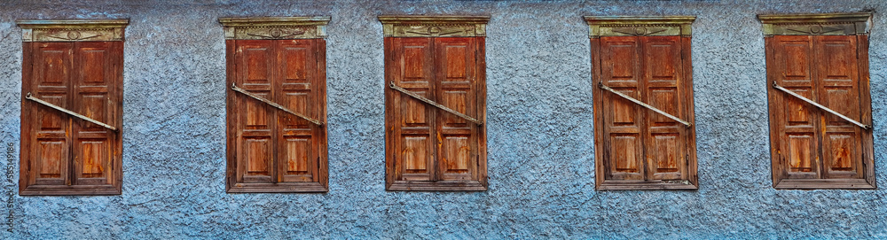Old shuttered windows on a rough blue wall Old shuttered windows on a rough blue wall